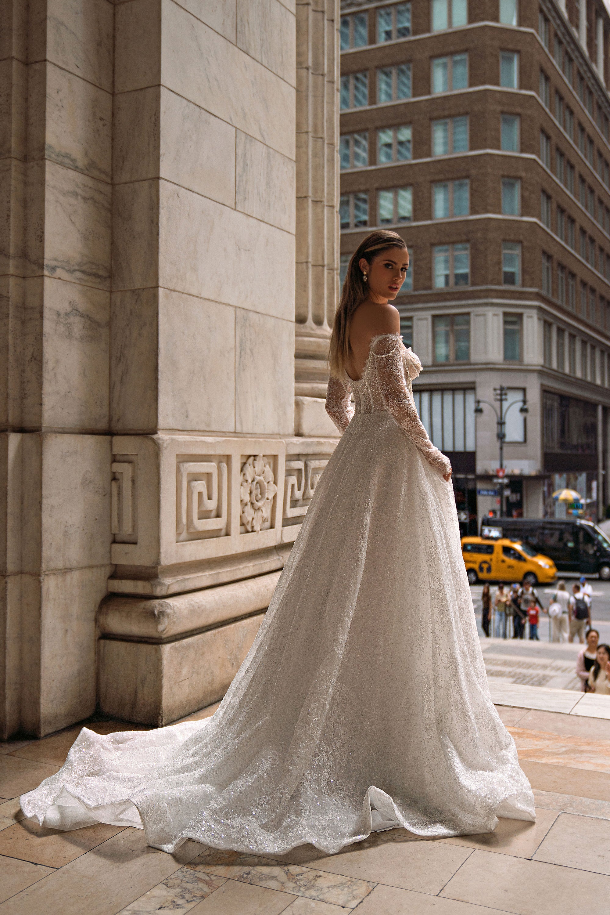 Back view of an ivory wedding dress with a low open back, long sleeves, and a long lace train
