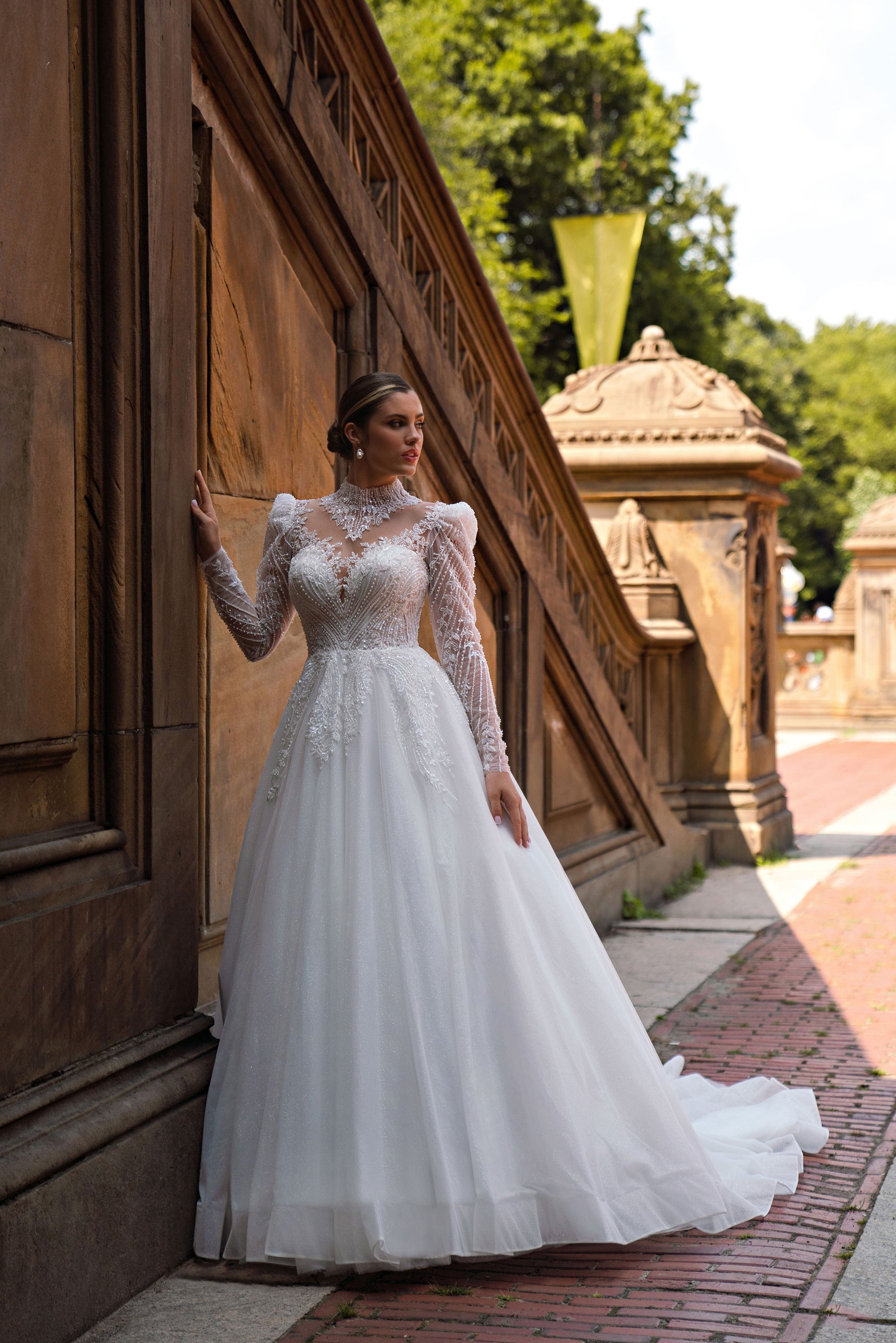 White A-line wedding dress with a high beaded neckline, sheer long sleeves, and a full sparkling skirt