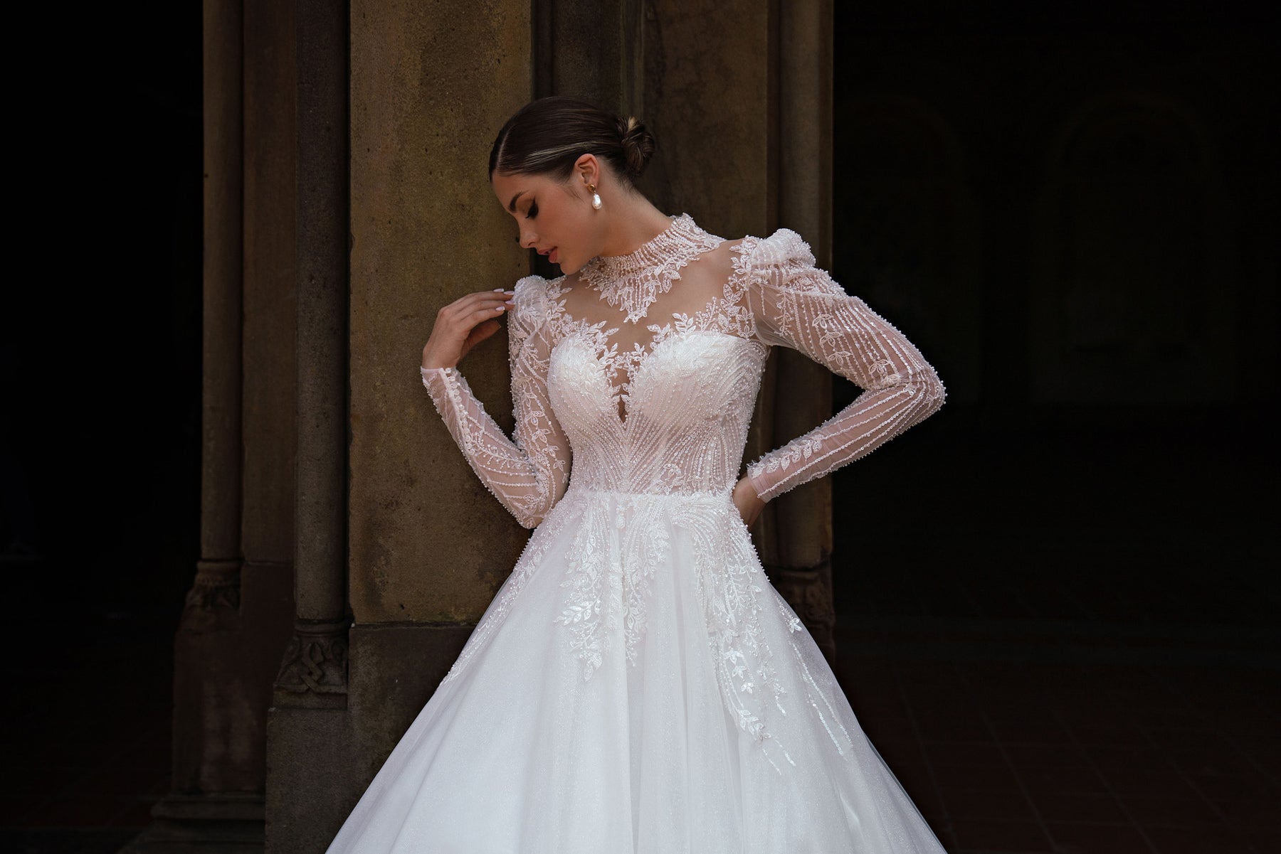 Close-up of a high illusion neckline, beaded bodice, and sheer lace sleeves on a white wedding dress