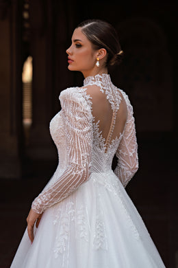 Back detail of a white wedding dress with a sheer beaded lace back, high neck, and long sleeves
