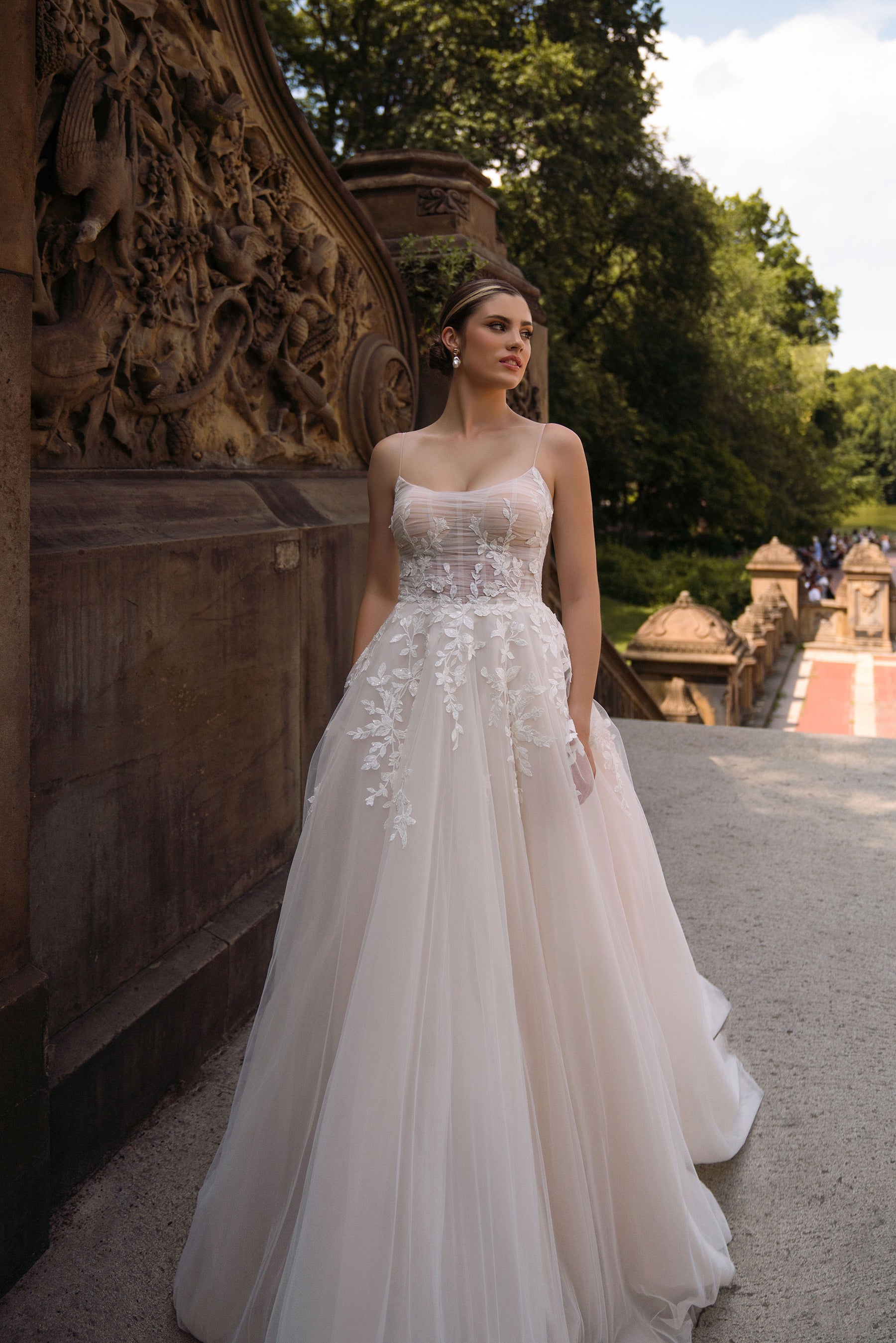 Ivory A-line wedding dress with thin straps, embellished bodice, floral appliqués, and a flowing skirt