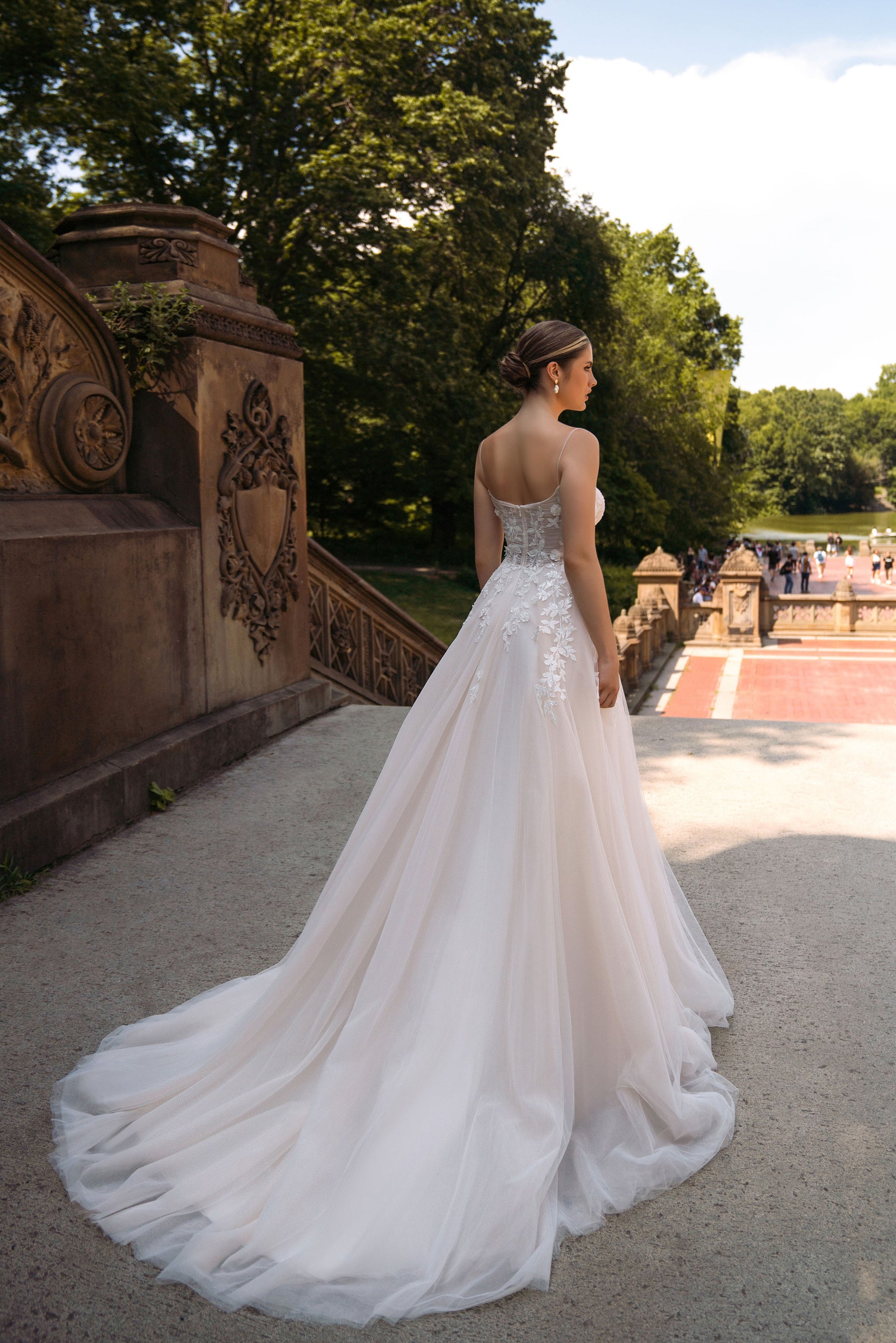 Back view of an ivory wedding dress with thin straps, floral appliqués, and a long flowing train