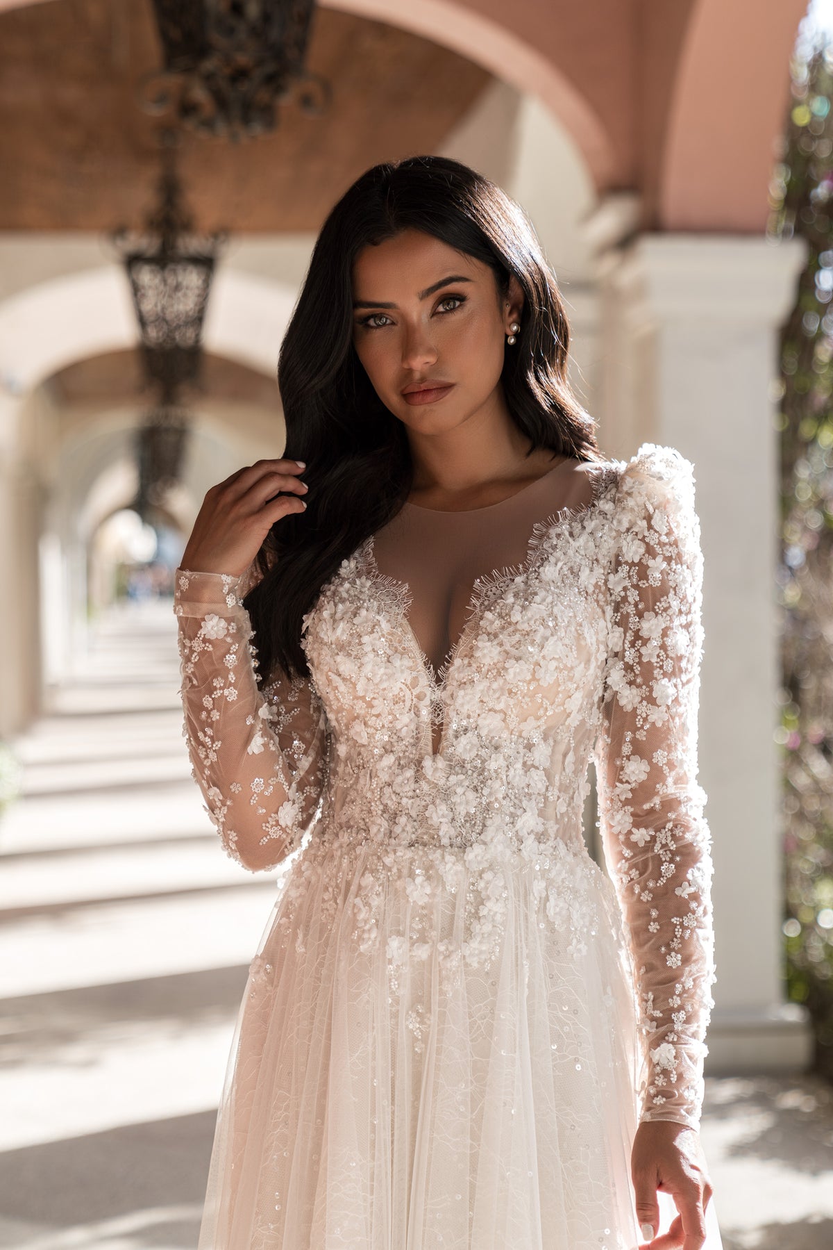 Ivory A-line wedding dress with a deep V-neckline, sheer long sleeves, and floral lace appliqués