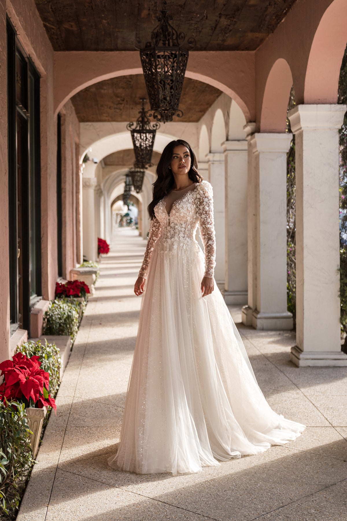 Floral lace A-line wedding dress with a deep V-neckline, long sheer sleeves, and a full flowing skirt