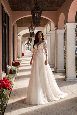 Floral lace A-line wedding dress with a deep V-neckline, long sheer sleeves, and a full flowing skirt