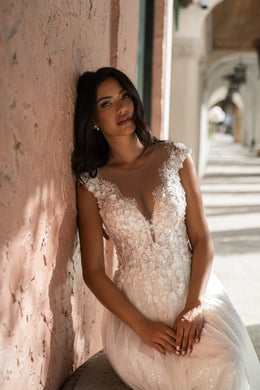 Close-up of an ivory wedding dress with floral lace on the bodice, a deep V-neckline, and cap sleeves
