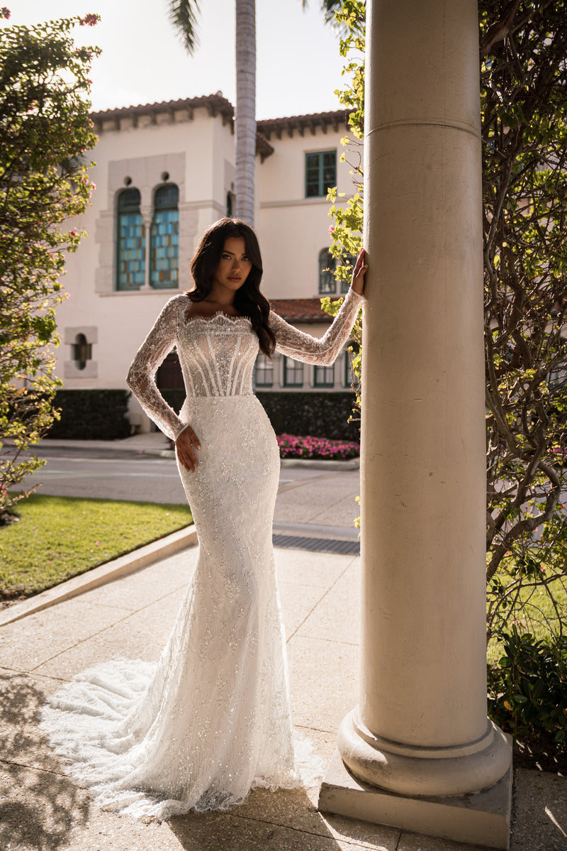 Ivory mermaid wedding dress with long sheer lace sleeves, sparkling beadwork, and a sweeping train