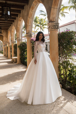 Ivory ball gown wedding dress with a beaded illusion bodice, long sheer sleeves, and a sweeping train