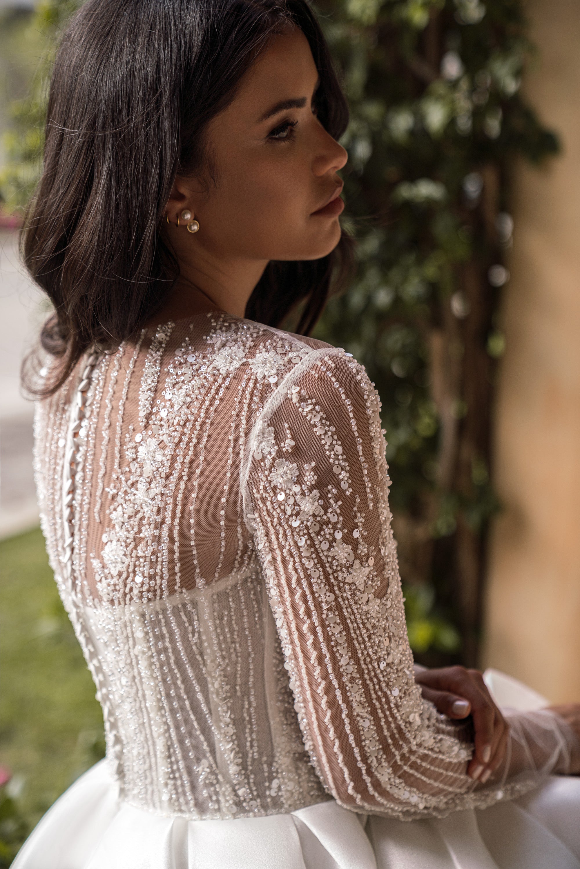 Sheer embellished back of an ivory wedding dress with striped beadwork and long illusion sleeves