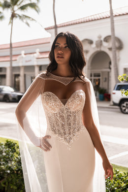 Ivory mermaid wedding dress with a sweetheart neckline, sparkling lace bodice, and sheer cape sleeves