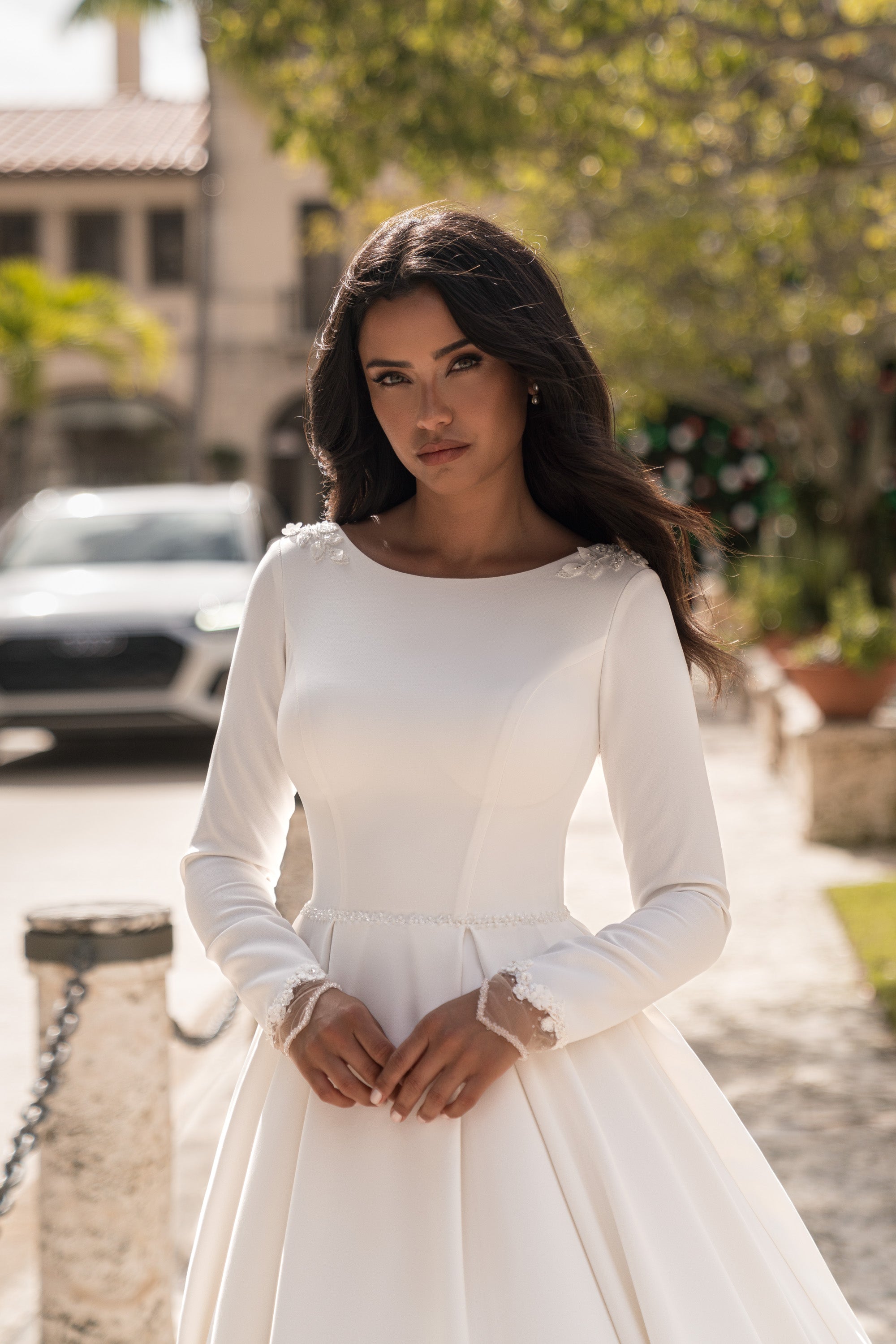 Ivory A-line wedding dress with a high rounded neckline, long sleeves, and lace-trimmed cuffs