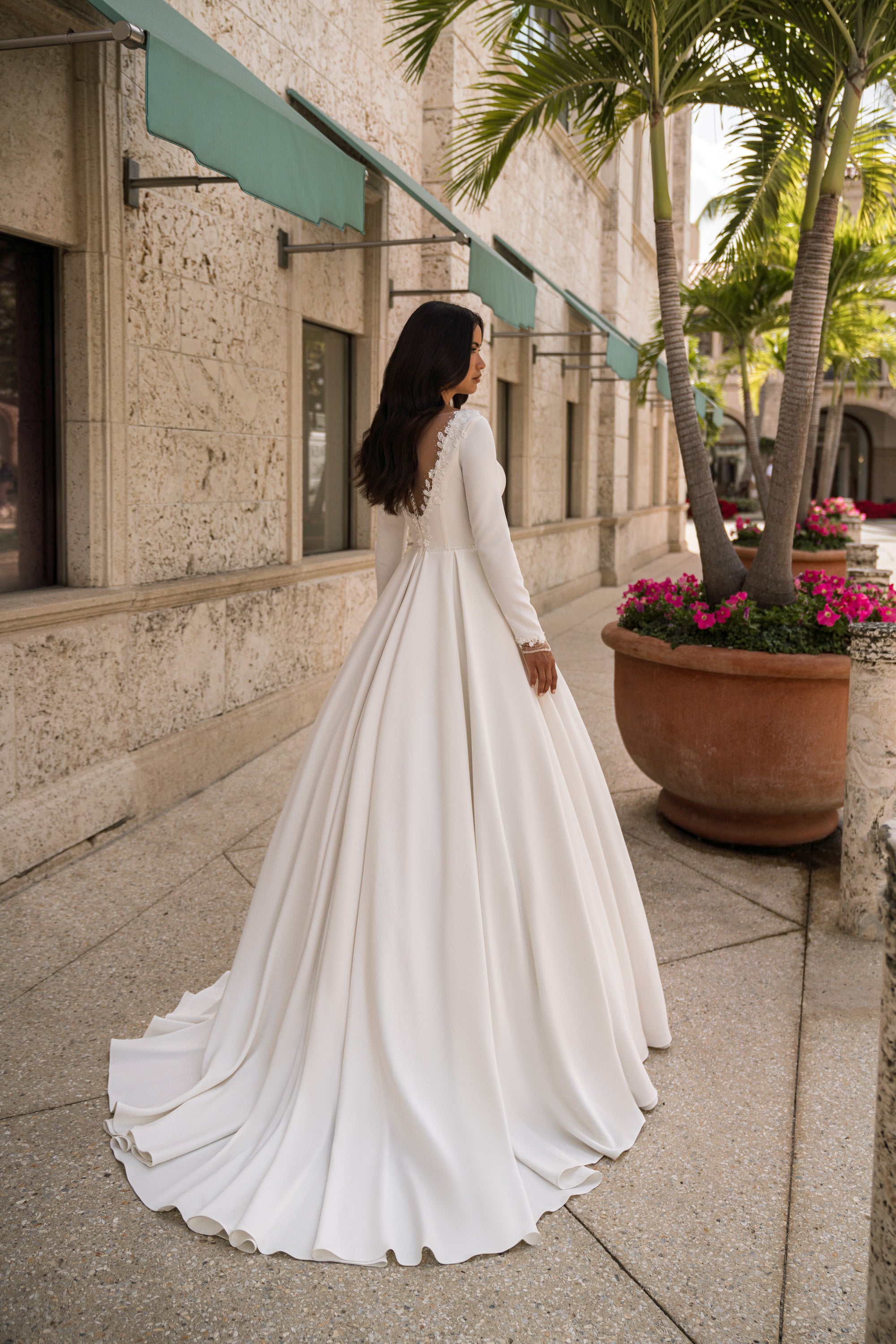 Ivory wedding dress showing an illusion lace back, long sleeves, and a sweeping floor-length train