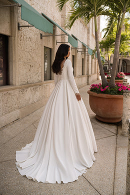 Ivory wedding dress showing an illusion lace back, long sleeves, and a sweeping floor-length train