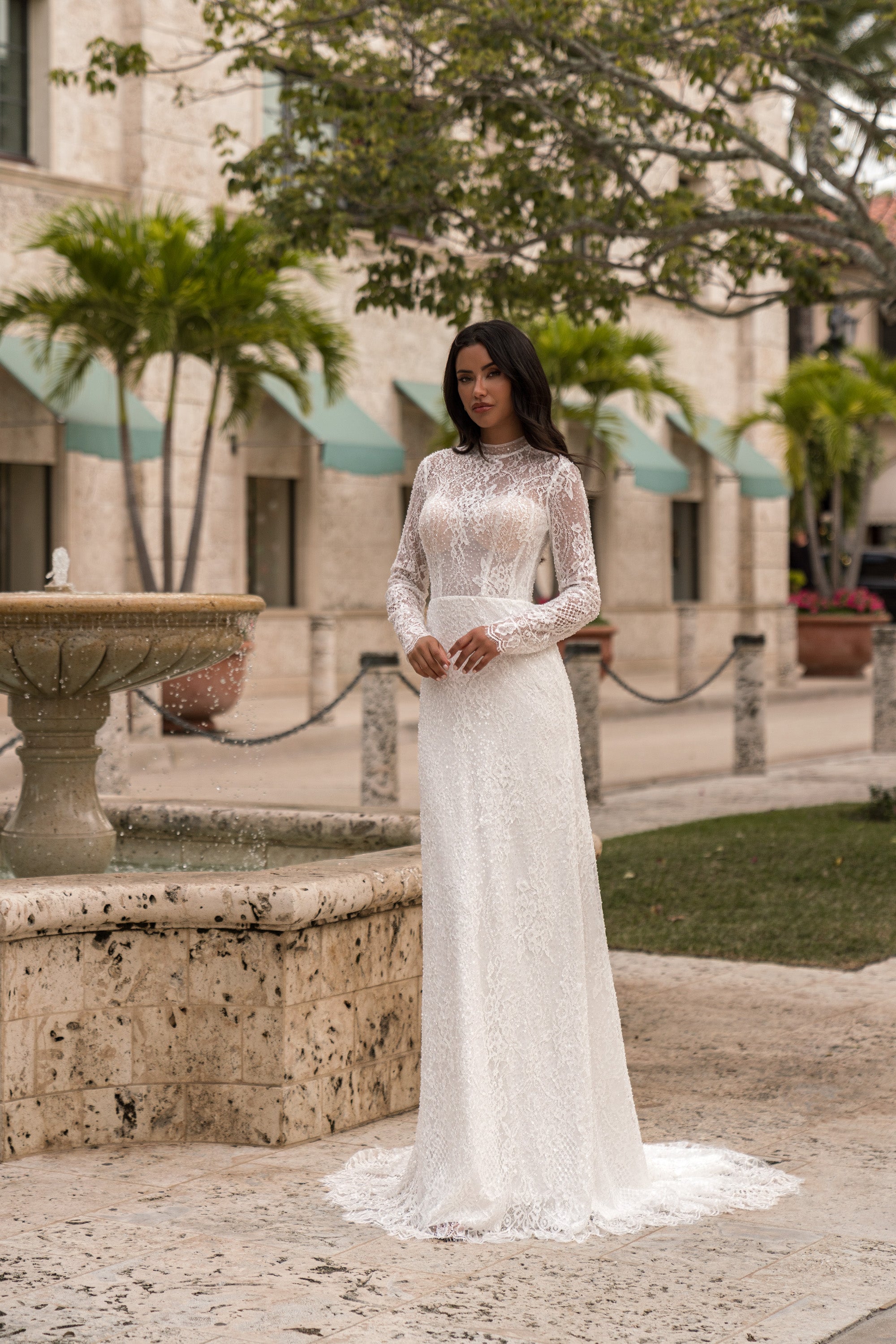 Ivory sheath wedding dress with a high neckline, long lace sleeves, and a delicate floor-length train
