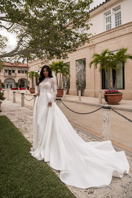 Ivory sheath wedding dress styled with a detachable full overskirt that spreads into a dramatic long train