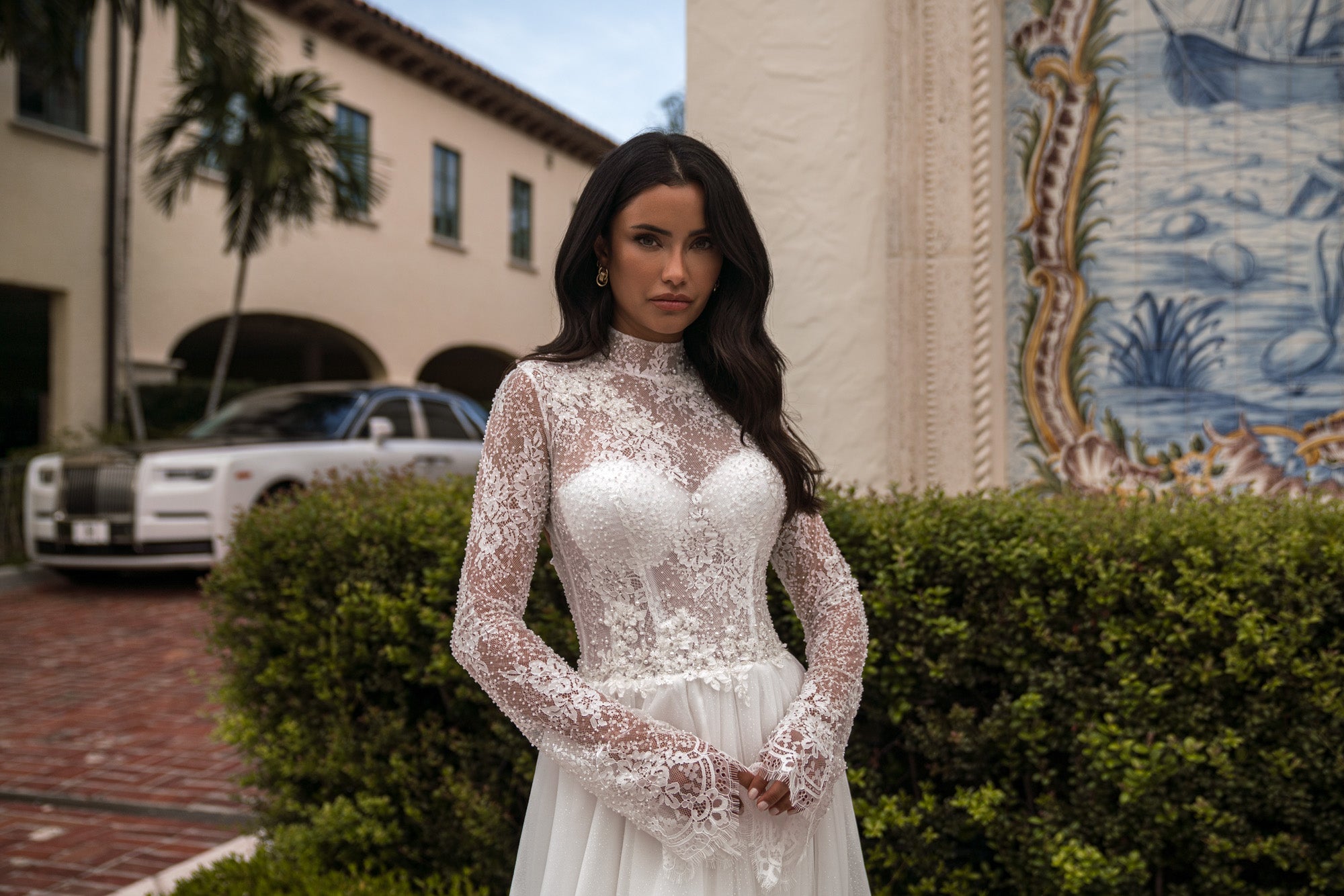 Close-up of an ivory wedding dress with a high sheer lace neckline, sleeves, and fitted bodice