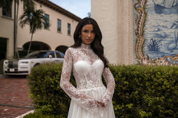 Close-up of an ivory wedding dress with a high sheer lace neckline, sleeves, and fitted bodice