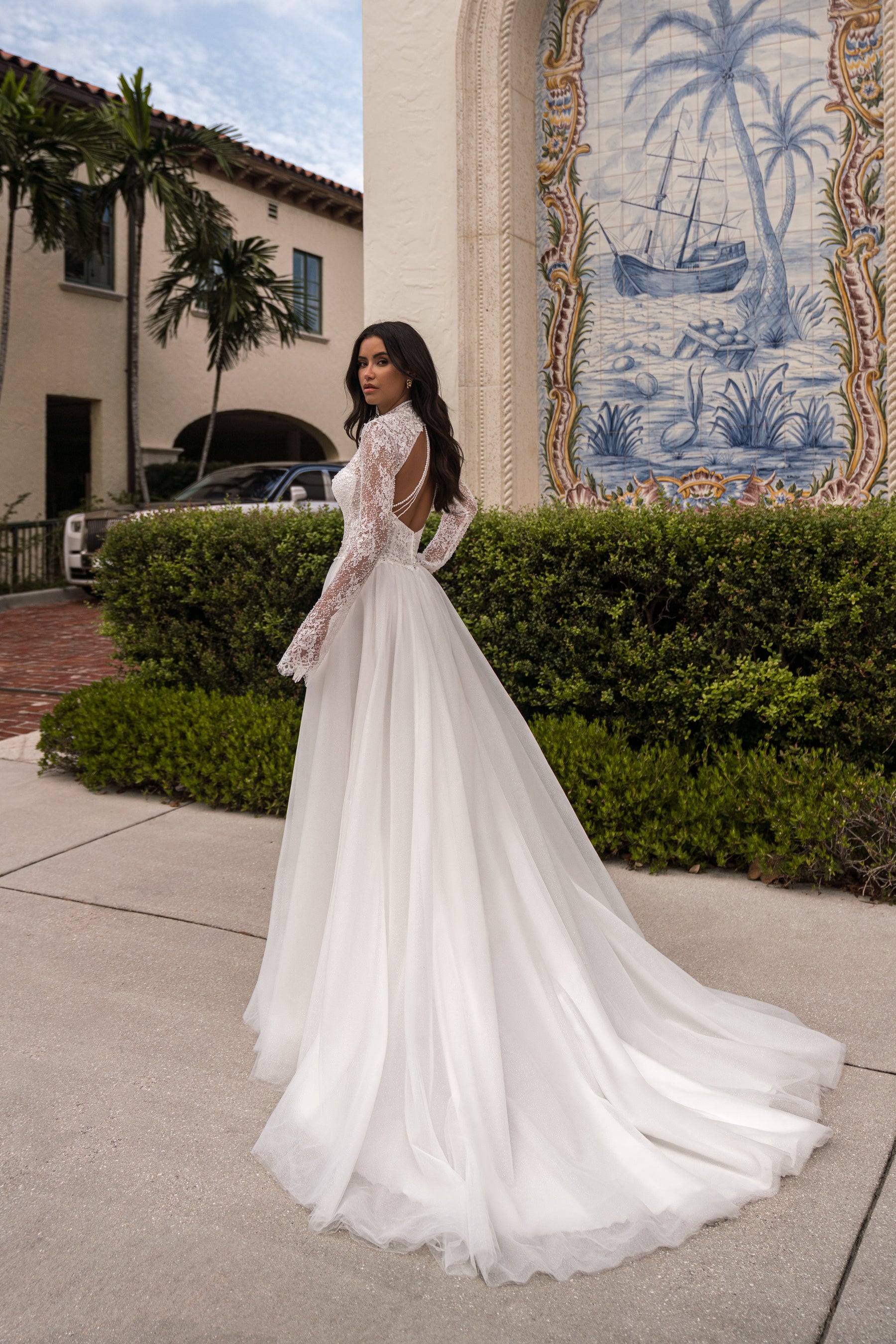 Open-back ivory wedding dress with long lace sleeves, an A-line skirt, and an extended train