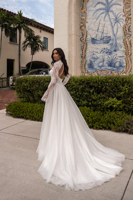 Open-back ivory wedding dress with long lace sleeves, an A-line skirt, and an extended train