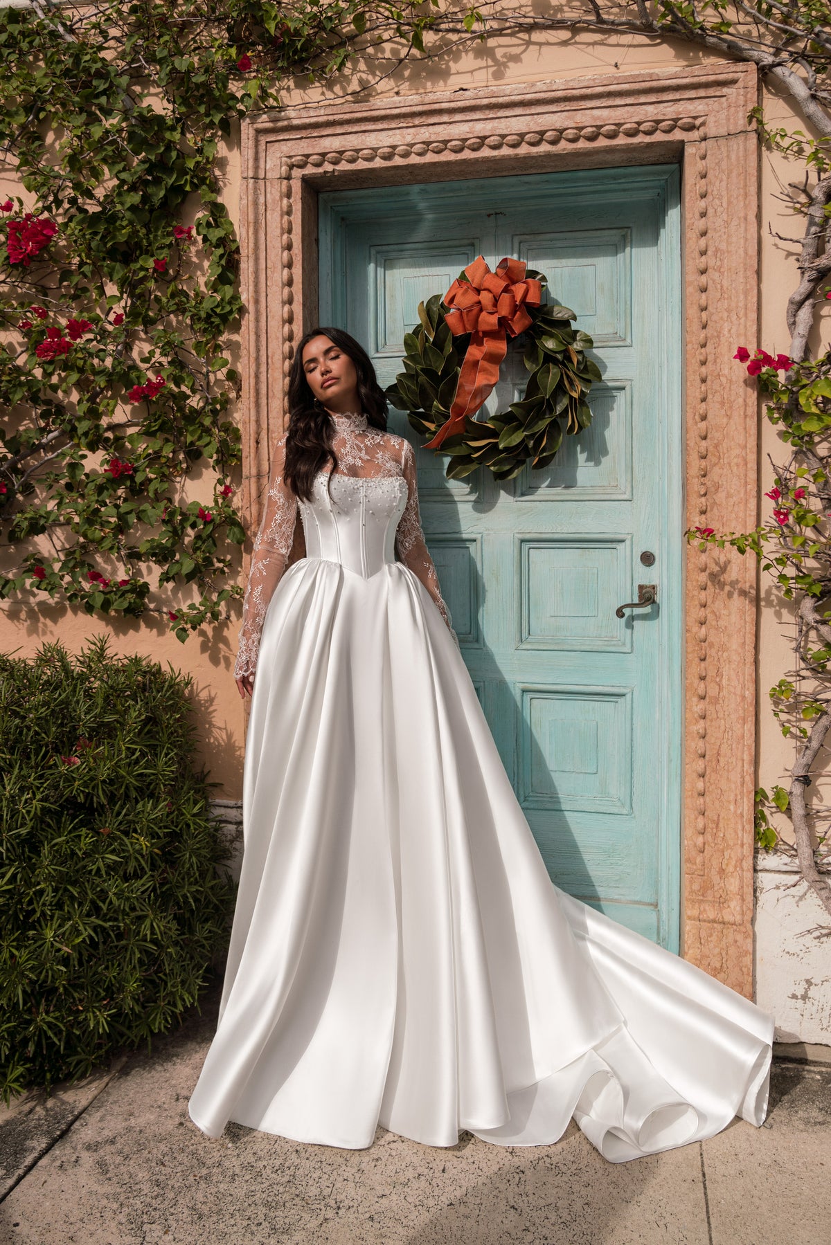 White ball-gown wedding dress with long lace sleeves, a fitted bodice, and an extended train pooling behind