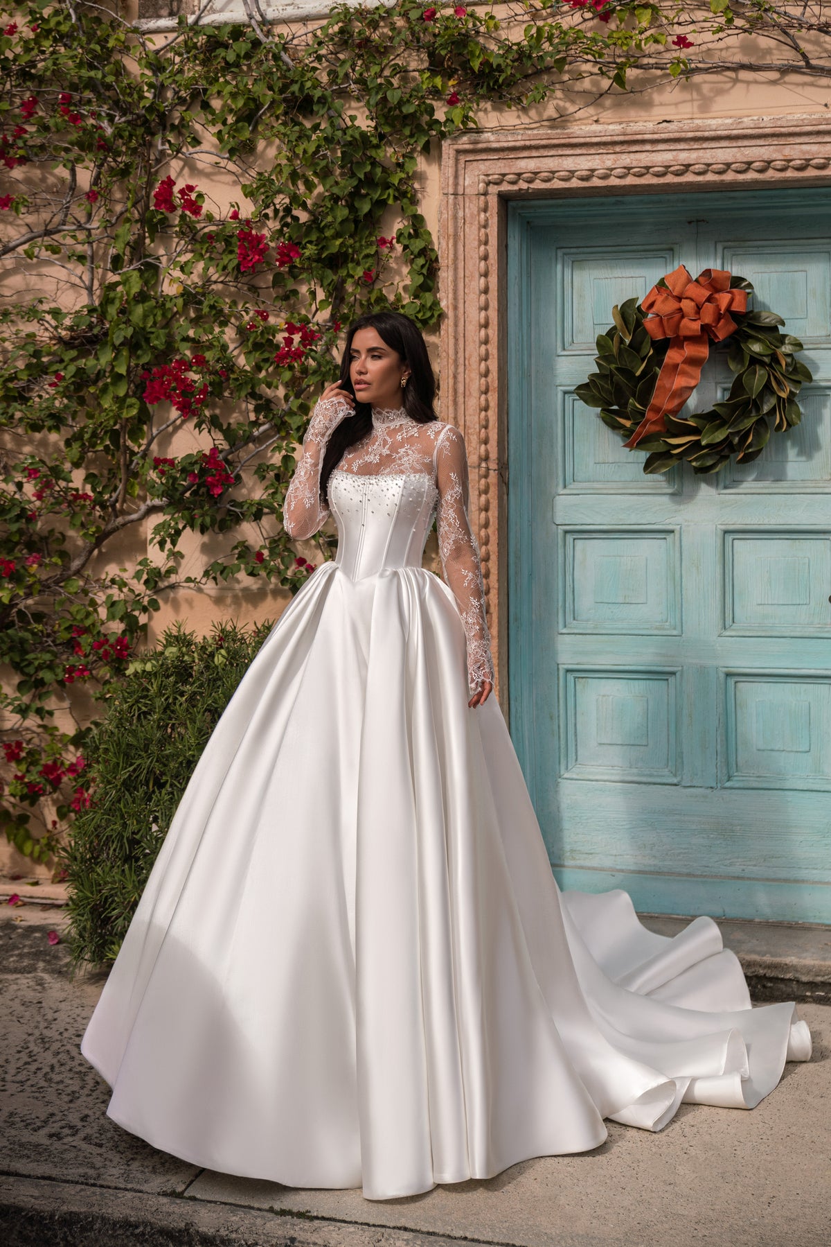 White wedding dress with a boned corset bodice, sheer lace sleeves, a wide full skirt, and trailing train