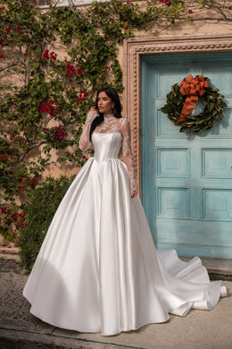 White wedding dress with a boned corset bodice, sheer lace sleeves, a wide full skirt, and trailing train
