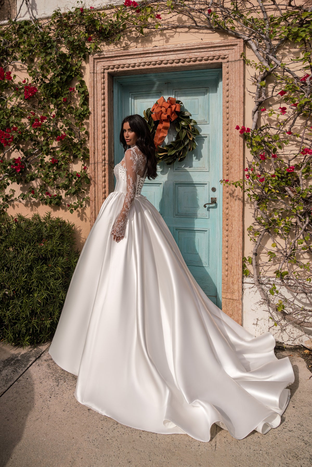 Profile of a white wedding dress with fitted lace sleeves, a full ball-gown skirt, and a long flowing train