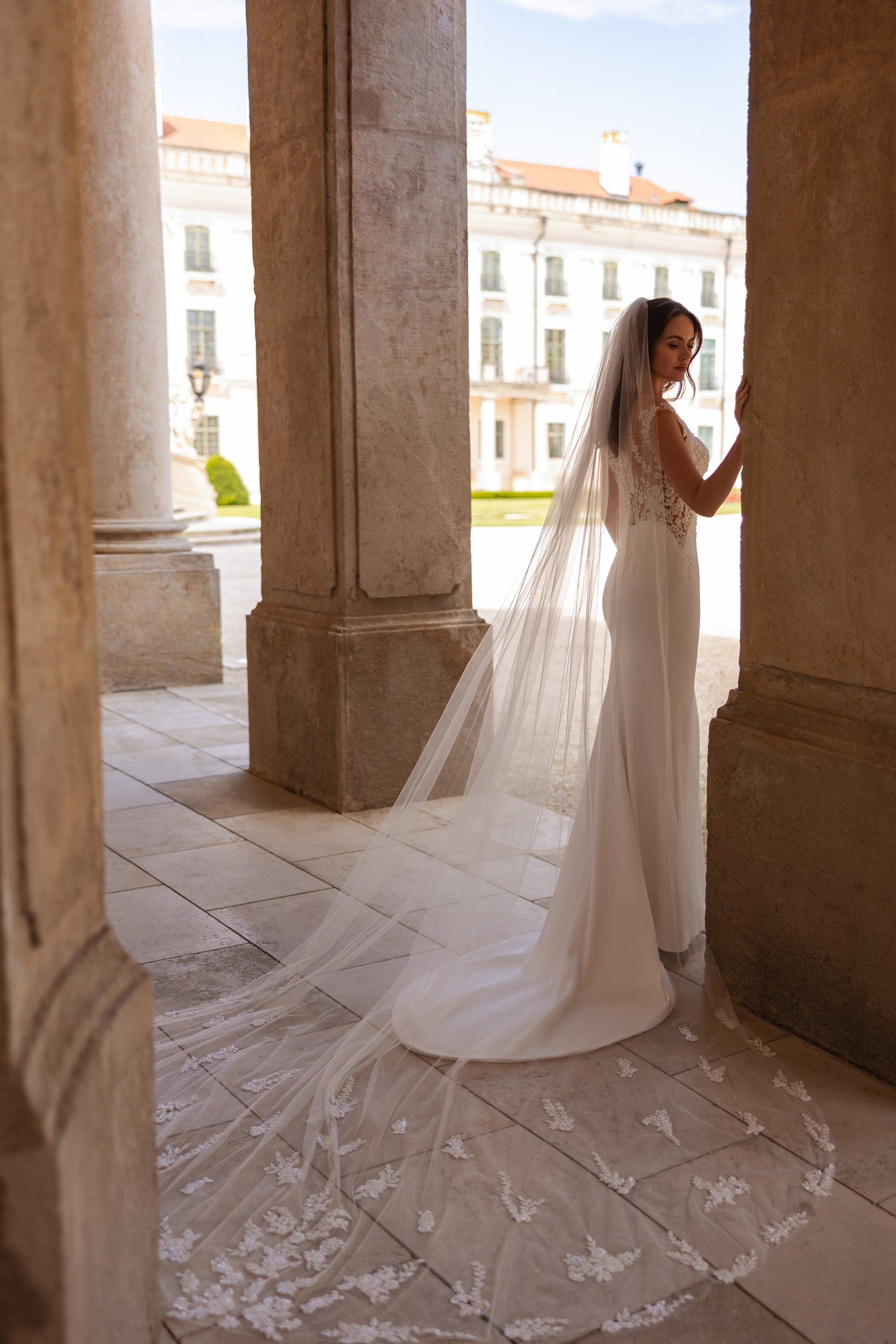 Sheer cathedral wedding veil with scattered floral lace appliqués extending into a floor-length train