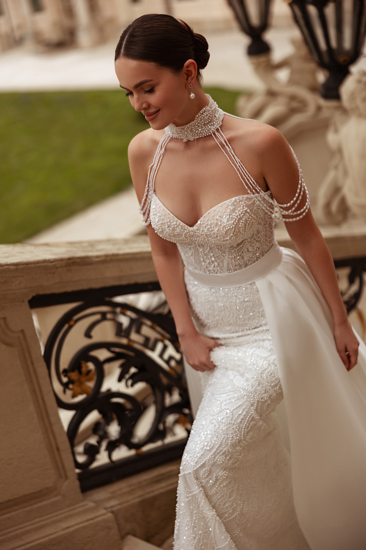Ivory wedding dress with a beaded sweetheart bodice, delicate shoulder chains, and a flowing overskirt