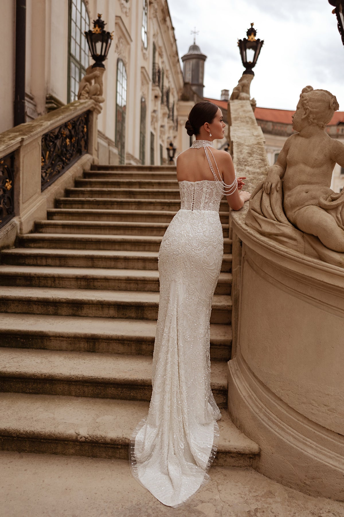 Open-back ivory wedding dress with beaded straps, a fitted silhouette, and a long trailing train