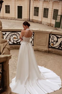 Back of an ivory wedding dress with an open beaded bodice and detachable overskirt forming a wide train