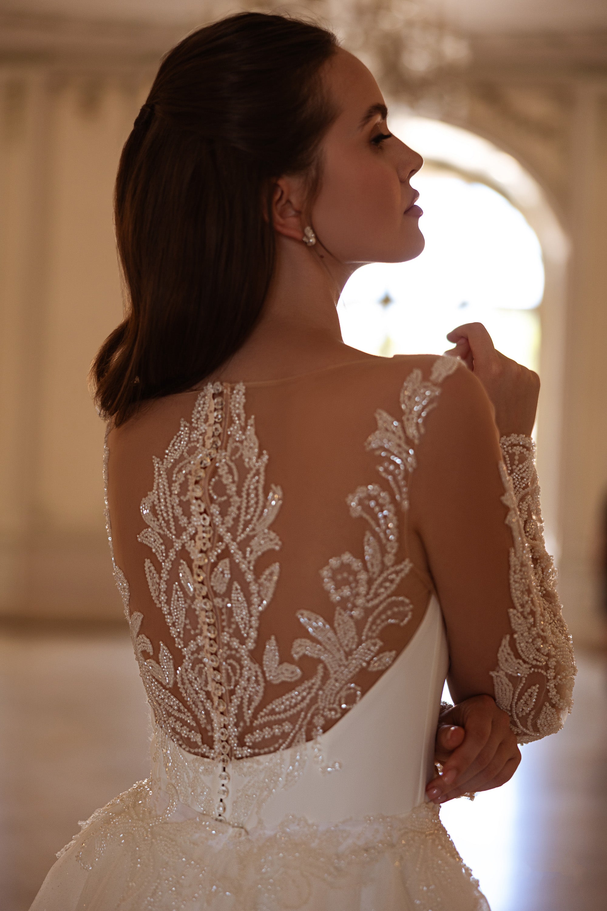 Close-up of an illusion lace back with floral beadwork and long sleeves on a wedding dress