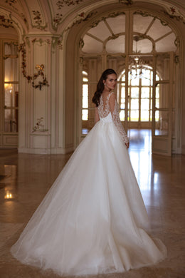 Wedding dress with an ornate illusion lace back, long sleeves, and a full glittering overskirt