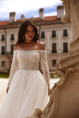 Close-up of an ivory wedding dress with a beaded lace bodice, off-the-shoulder neckline, and long sleeves
