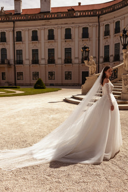 Side view of an ivory wedding dress with off-the-shoulder lace sleeves, a full skirt, and an extended train