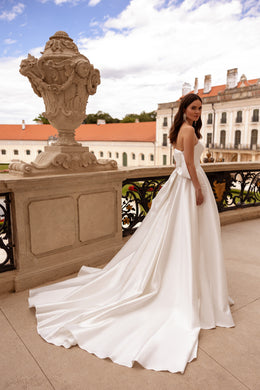 Side profile of an ivory strapless wedding dress with a fitted bodice and long train