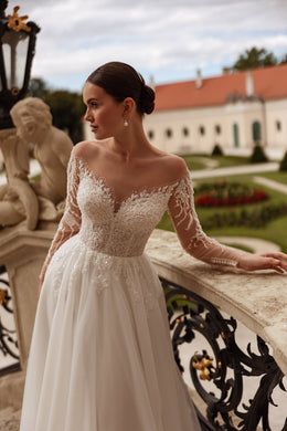 Ivory A-line wedding dress with an off-the-shoulder neckline, beaded lace sleeves, and a sheer bodice