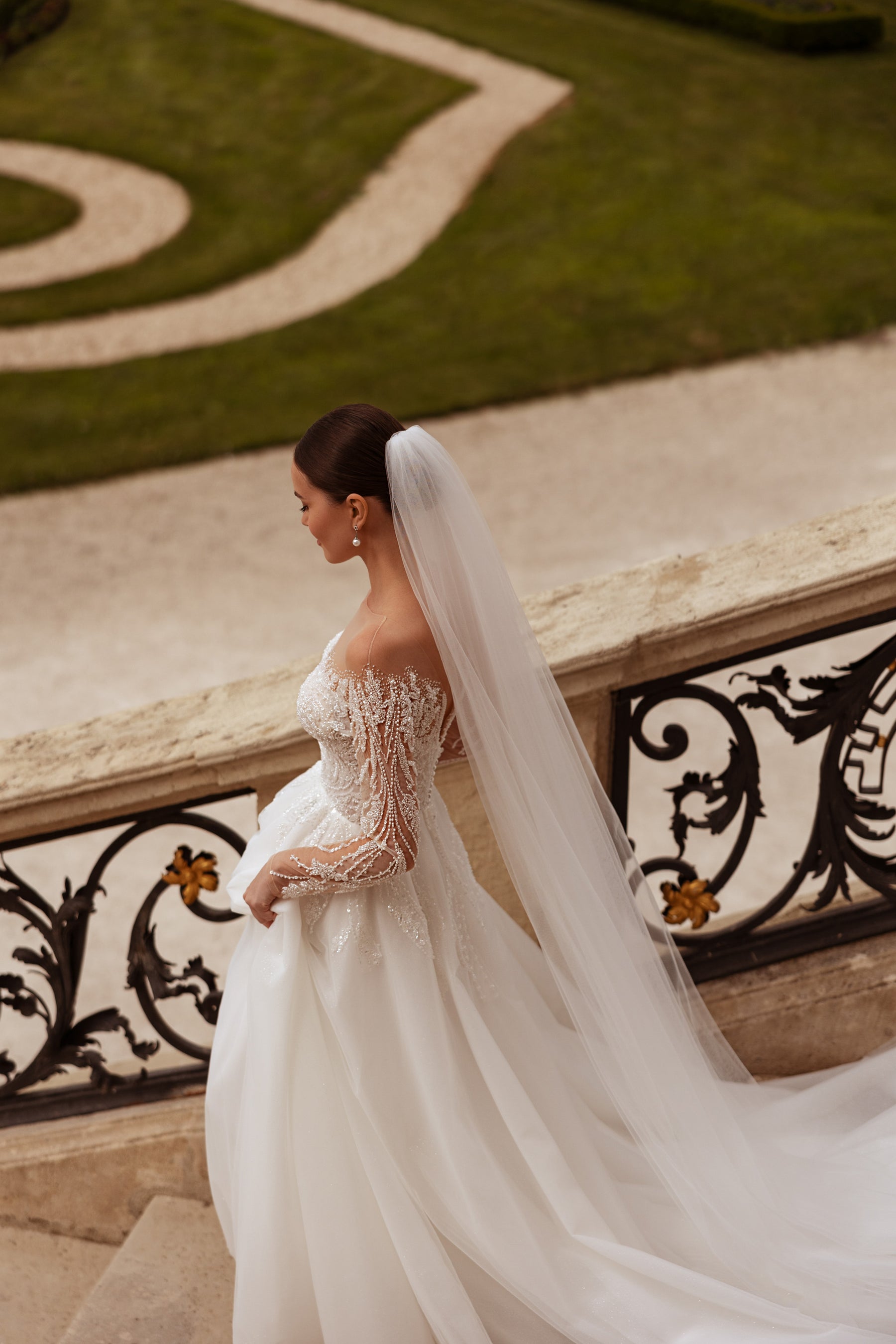 Ivory wedding dress with sheer beaded lace sleeves, a flowing A-line skirt, and a long train