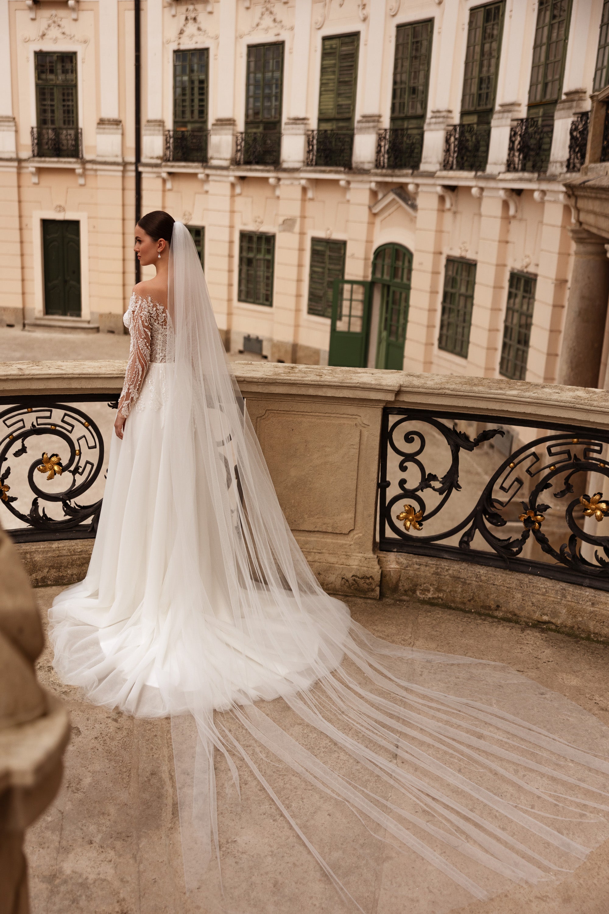 Full-length ivory wedding dress with beaded lace sleeves, a flowing skirt, and an extended train
