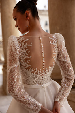 Illusion lace back with floral appliqués and covered buttons on a long-sleeve wedding dress