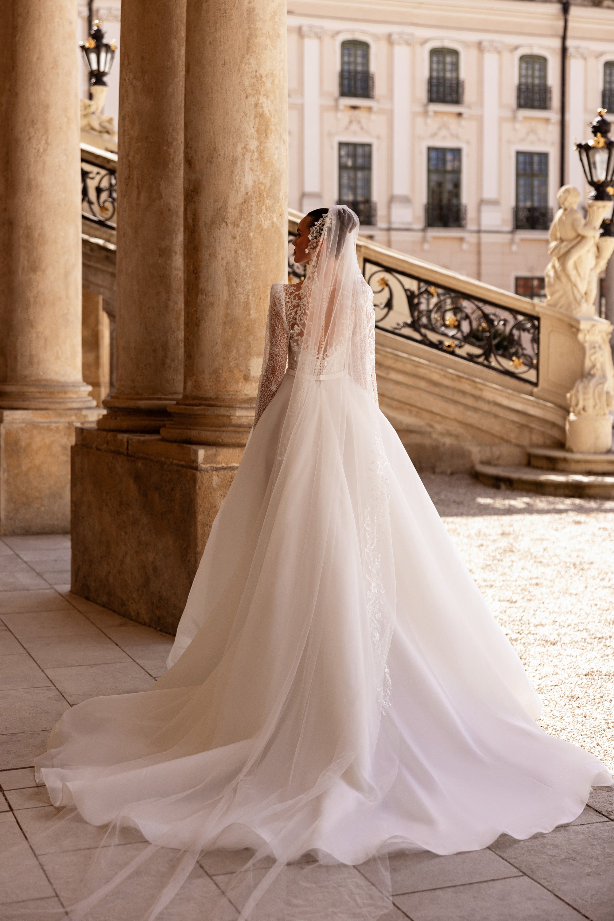 Ivory wedding dress with sheer lace sleeves, a full skirt, and a long flowing train