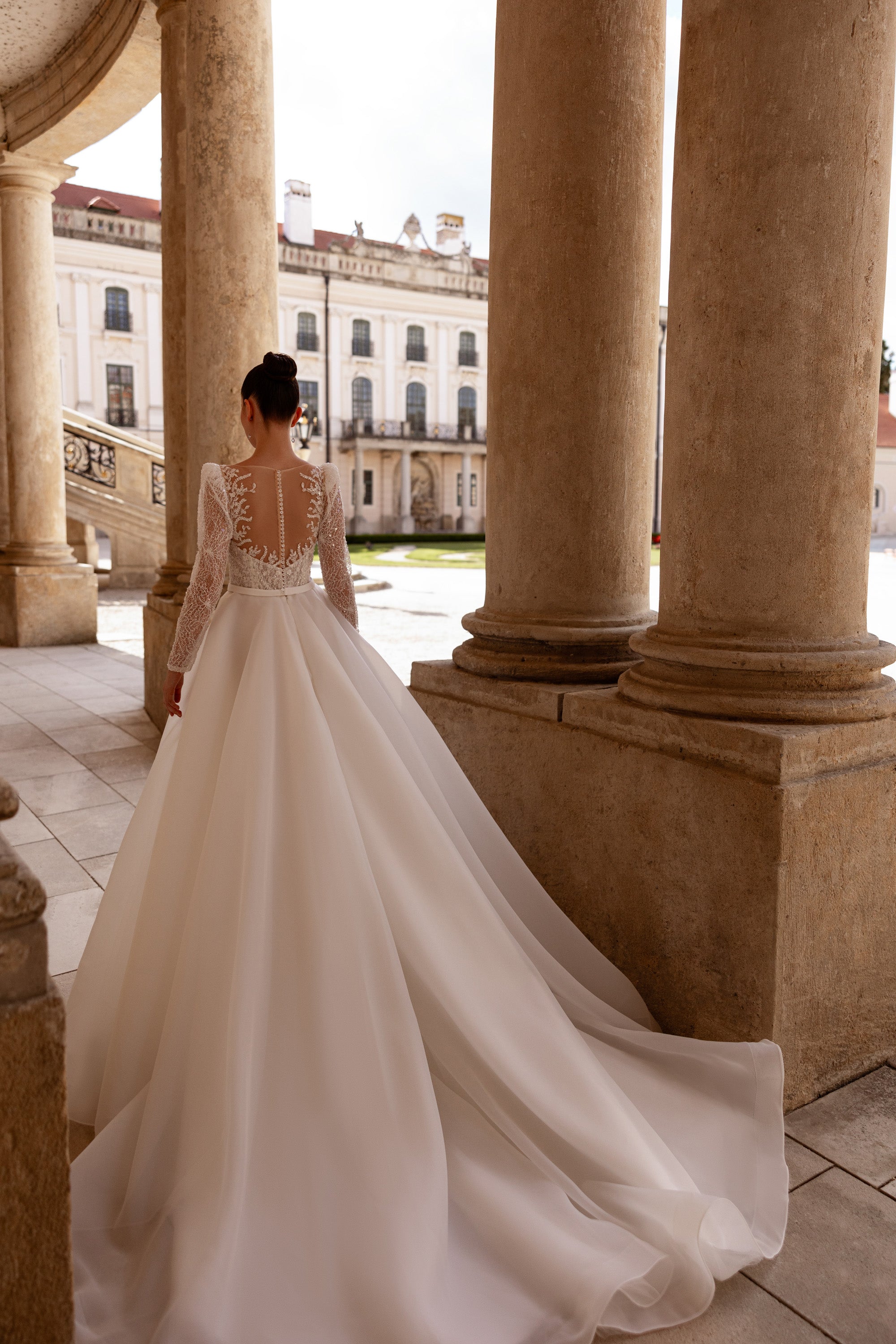 Back of an ivory wedding dress with a sheer lace bodice, long sleeves, and an extended train