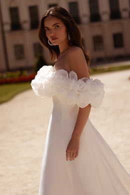 White strapless wedding dress with voluminous floral off-shoulder sleeves and a flowing skirt