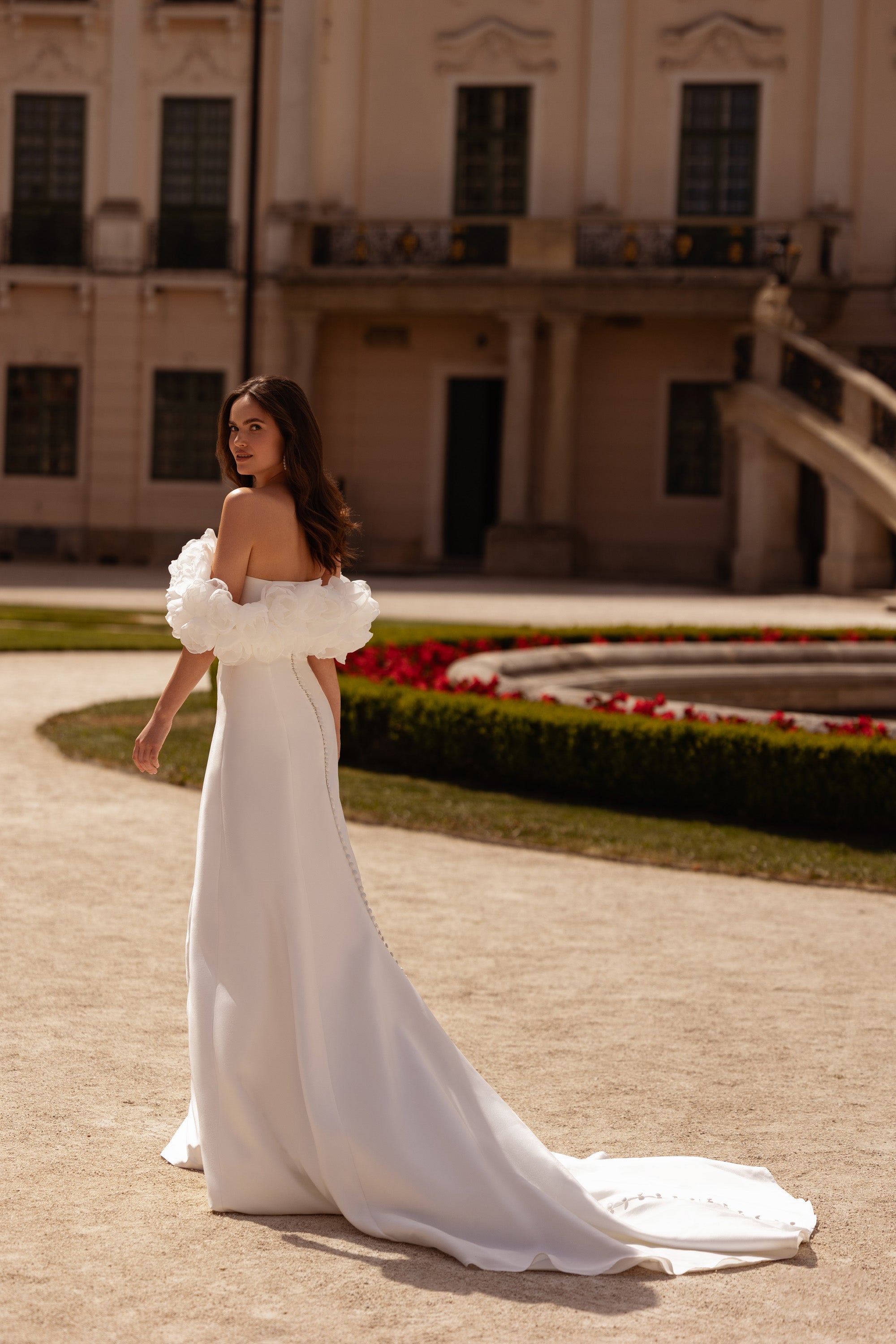 White wedding dress with floral off-shoulder sleeves, a smooth back, and a long trailing train