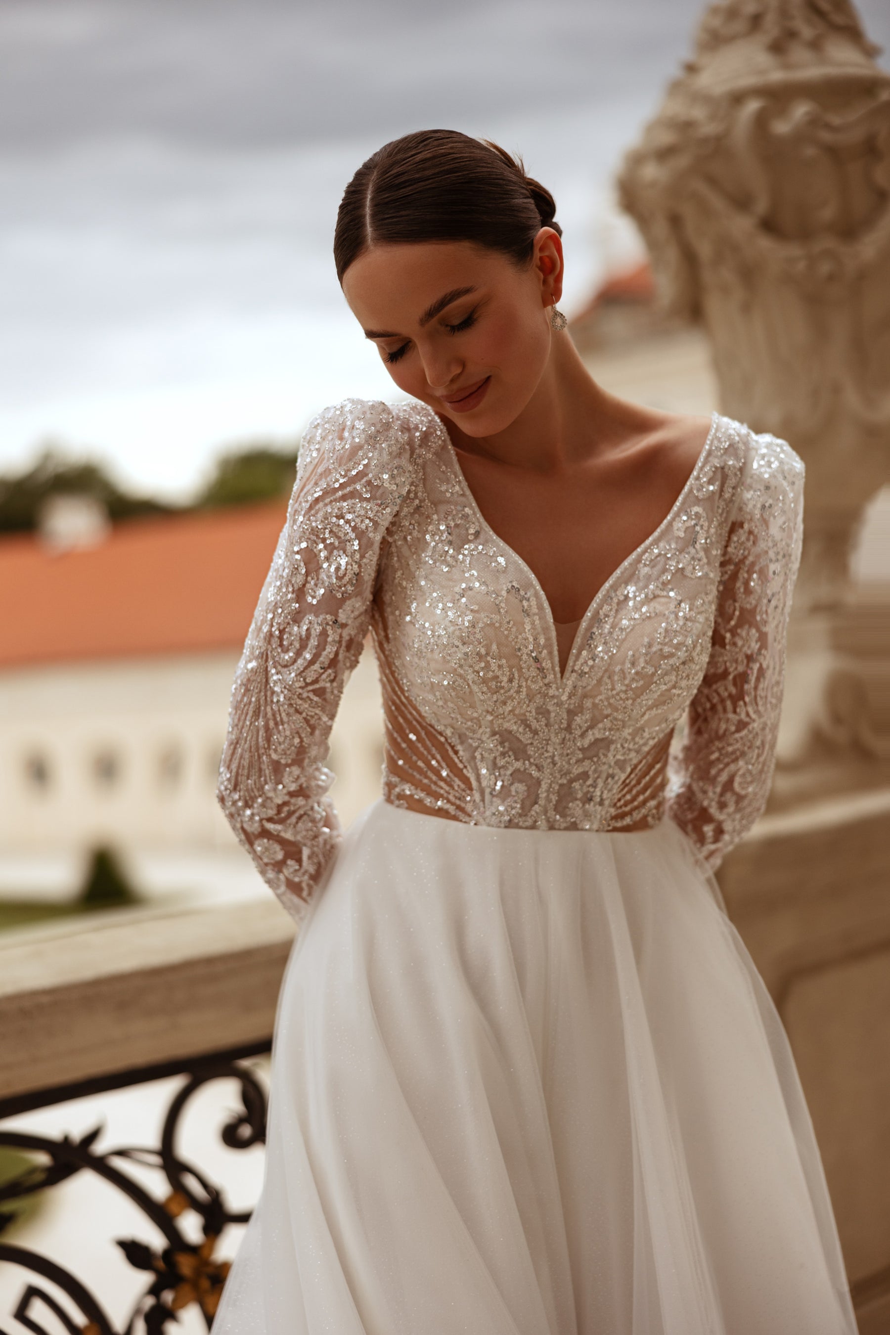 Plunging V-neck ivory wedding dress with long sheer lace sleeves and a sparkling beaded bodice