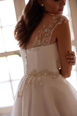Close-up of the beaded illusion back, covered buttons, and waist detail on an ivory wedding dress