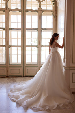 Ivory wedding dress with a low embellished back, full A-line skirt, and sweeping train