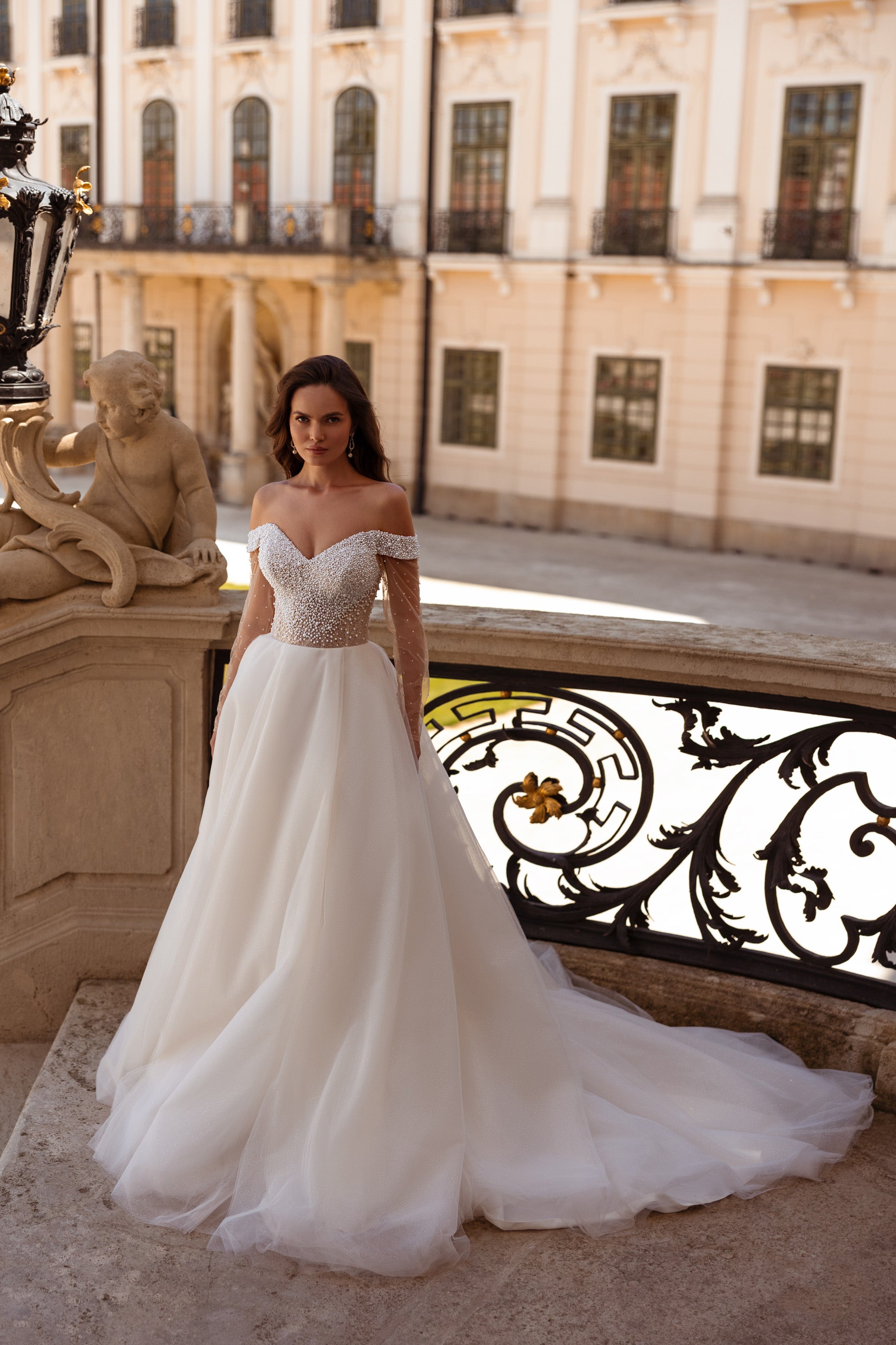 Ivory ball gown wedding dress with a pearl-beaded off-shoulder bodice and flowing full skirt