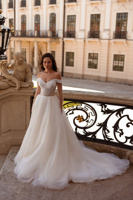 Ivory ball gown wedding dress with a pearl-beaded off-shoulder bodice and flowing full skirt