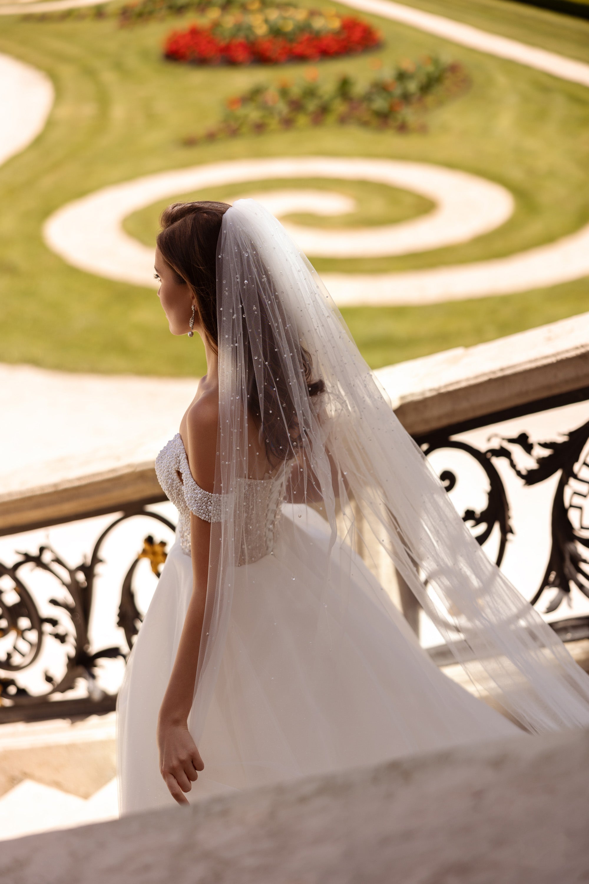 Side view of an ivory wedding dress with an off-shoulder pearl-beaded bodice and long flowing skirt